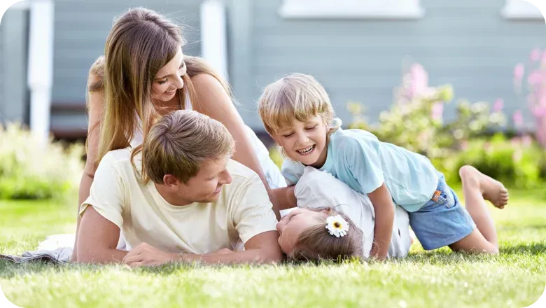 family laying down on healthy green lawn laughing